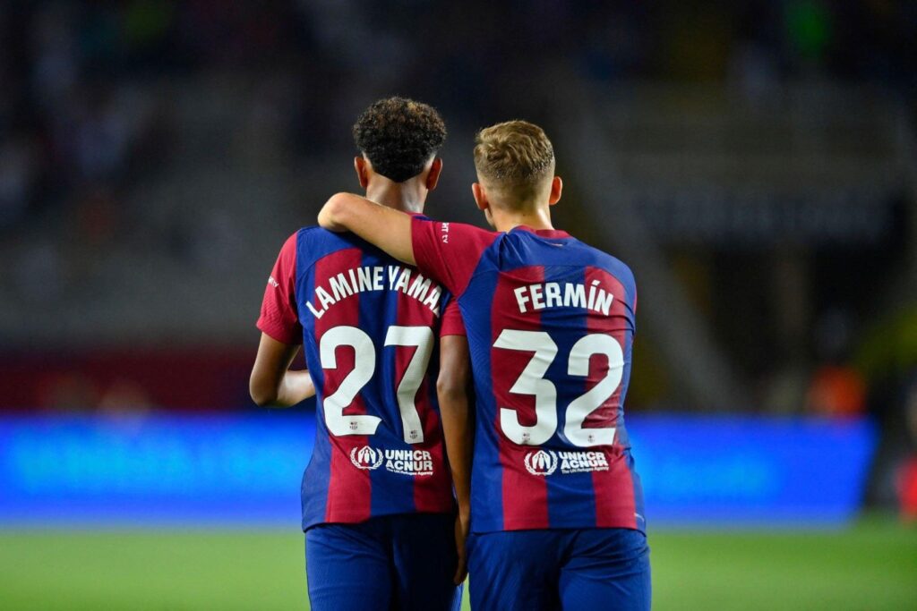 Barcelona's Spanish forward #27 Lamine Yamal and Barcelona's Spanish midfielder #32 Fermin Lopez celebrate Sevilla's Spanish defender #04 Sergio Ramos' owngoal during the Spanish Liga football match between FC Barcelona and Sevilla FC at the Estadi Olimpic Lluis Companys in Barcelona on September 29, 2023.