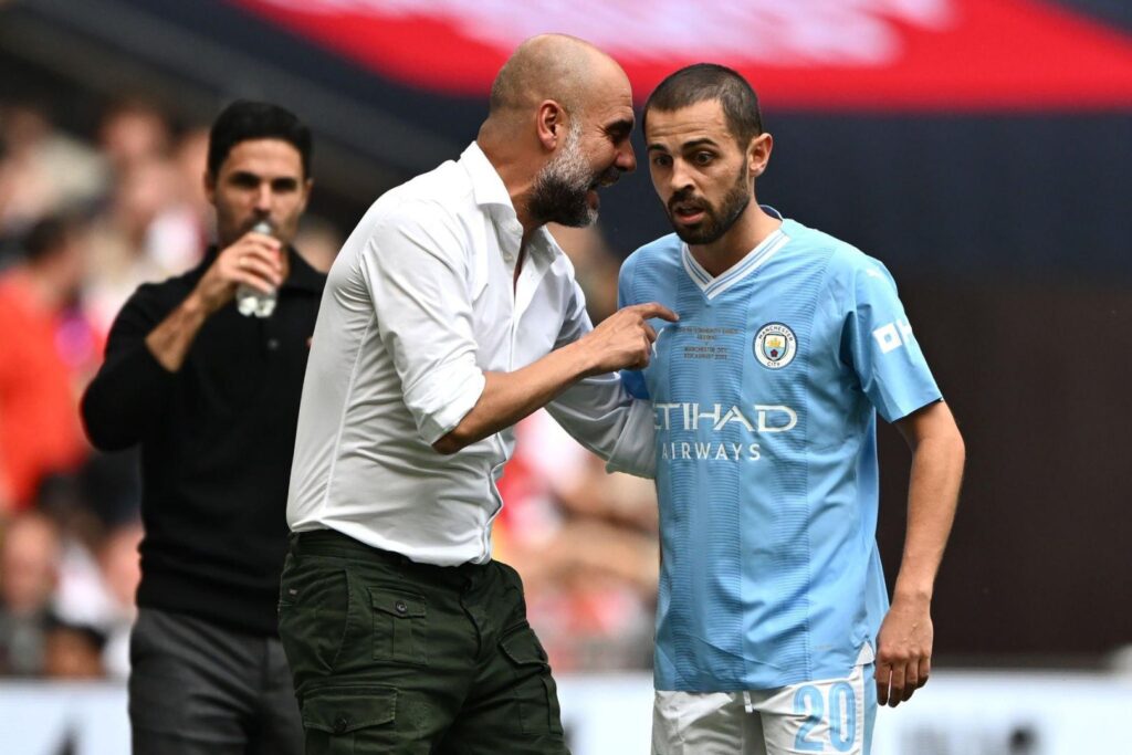 LONDON, ENGLAND - AUGUST 06: Pep Guardiola, Manager of Manchester City ( Former Barcelona coach ) speaks with Bernardo Silva of Manchester City during The FA Community Shield match between Manchester City against Arsenal at Wembley Stadium on August 06, 2023 in London, England.