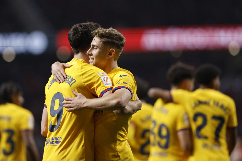 Barcelona's Spanish midfielder #32 Fermin Lopez celebrates scoring his team's third goal with Barcelona's Polish forward #09 Robert Lewandowski during the Spanish league football match between Club Atletico de Madrid and FC Barcelona at the Metropolitano stadium in Madrid on March 17, 2024.