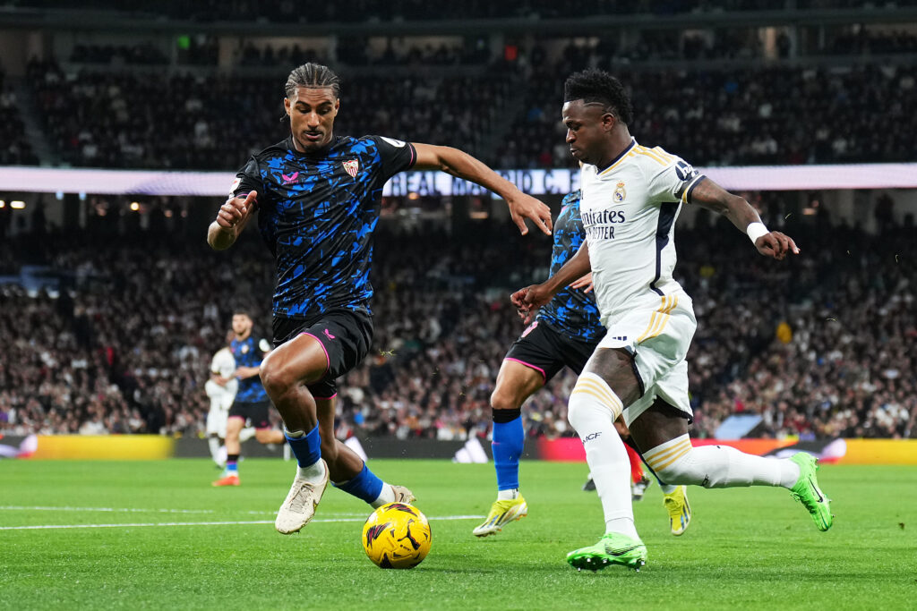 MADRID, SPAIN - FEBRUARY 25: Vinicius Junior of Real Madrid battles for possession with Loic Bade of Sevilla FC during the LaLiga EA Sports match between Real Madrid CF and Sevilla FC at Estadio Santiago Bernabeu on February 25, 2024 in Madrid, Spain.