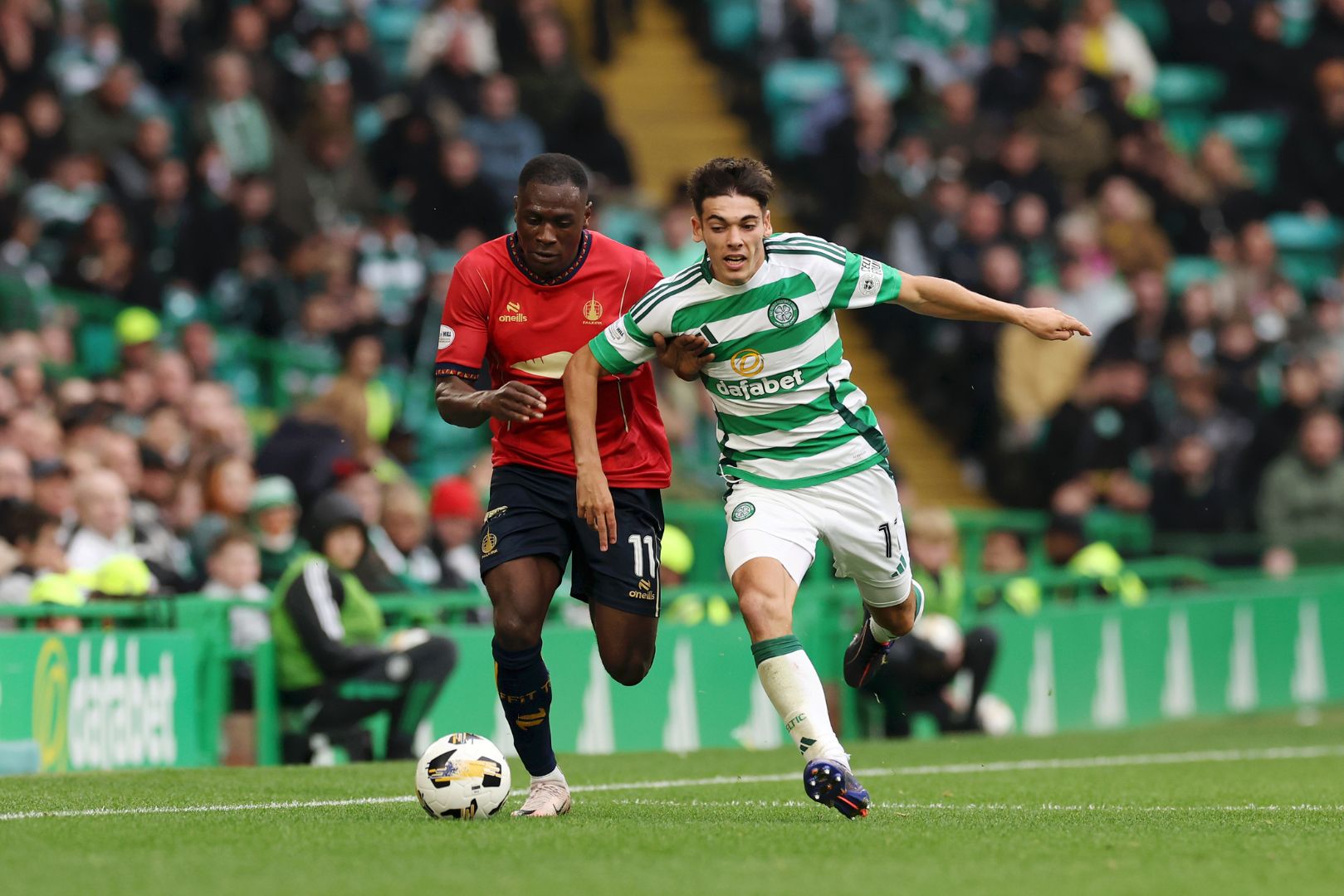 GLASGOW, SCOTLAND - SEPTEMBER 22: Barcelona loanee Alex Valle who is now playing at Celtic on loan is challenged by Alfie Agyeman of Falkirk FC during the Premier Sports Cup Quarter Final between Celtic and Falkirk at Celtic Park on September 22, 2024 in Glasgow, Scotland.