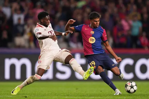 BARCELONA, SPAIN - OCTOBER 23: Lamine Yamal of FC Barcelona shoots whilst under pressure from Alphonso Davies of Bayern Munich during the UEFA Champions League 2024/25 League Phase MD3 match between FC Barcelona and FC Bayern Munchen at Estadi Olimpic Lluis Companys on October 23, 2024 in Barcelona, Spain.