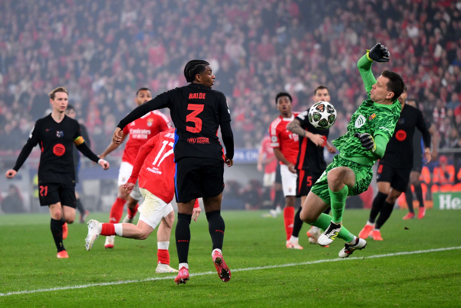 LISBON, PORTUGAL - MARCH 05: Wojciech Szczesny of FC Barcelona saves a shot from Muhammed Kerem Aktuerkoglu of SL Benfica (obscured) as Alejandro Balde of FC Barcelona looks on during the UEFA Champions League 2024/25 Round of 16 first Leg match between SL Benfica and FC Barcelona at Estadio da Luz on March 05, 2025 in Lisbon, Portugal.