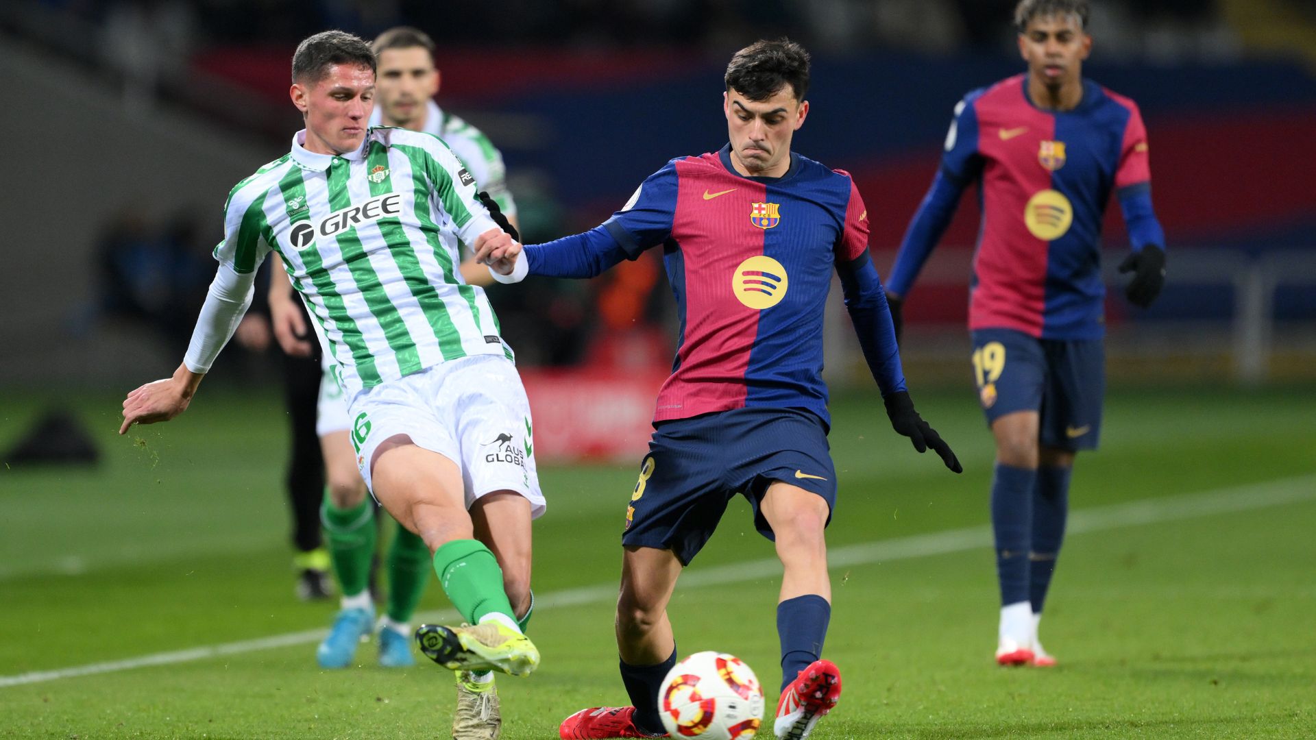 Sergi Altimira of Real Betis passes the ball whilst under pressure from Pedri of FC Barcelona during the Copa del Rey Round of 16 match between FC Barcelona and Real Betis at Estadi Olimpic Lluis Companys on January 15, 2025 in Barcelona, Spain.